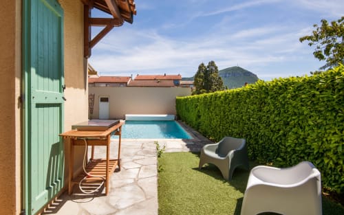 Private villa pool garden in Millau with lounge chairs, green hedges, and mountain views