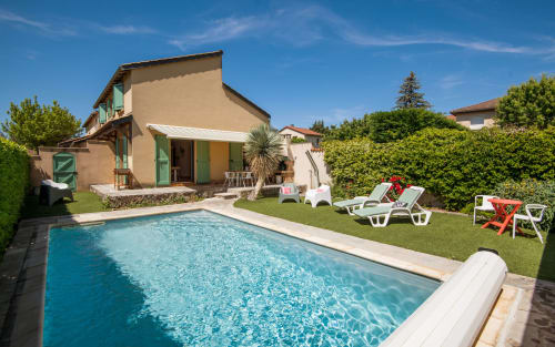 Private villa in Millau with outdoor swimming pool, green lawn, lounge chairs, and terrace with green shutters