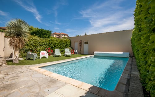 Private villa pool in Millau with lounge chairs, manicured garden, and Mediterranean-style courtyard surrounded by hedges