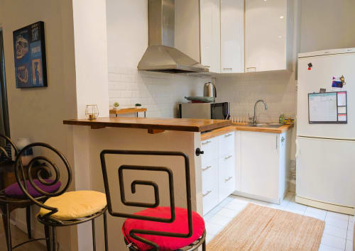 Modern kitchen in Paris apartment with white cabinets, wooden countertop, and contemporary seating at counter
