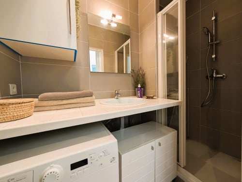 Modern bathroom with white sink, mirror, and washer-dryer in Paris apartment