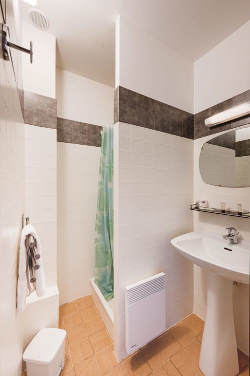 Salle de bain moderne à la Chambre Provence de l'Hôtel Restaurant Le Verdon avec carrelage blanc, frise de carreaux sombres, lavabo sur colonne, et