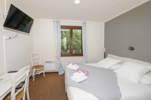 Chambre Provence à l'Hôtel Restaurant Le Verdon avec lit, télévision, vue sur les fenêtres et draps blancs
