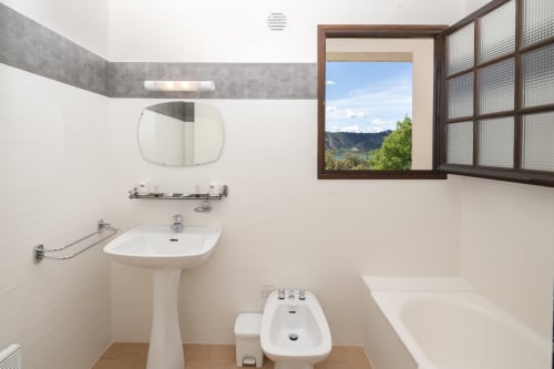 Salle de bains moderne de l'Hôtel Le Verdon avec lavabo sur pied, miroir, baignoire et vue sur le lac par la fenêtre aux Salles-sur-Mer