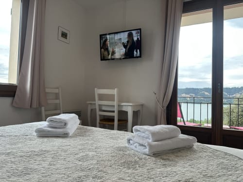 Chambre moderne de l'Hôtel Restaurant Le Verdon avec vue sur le lac, serviettes blanches sur le lit, télévision murale et paysage aquatique