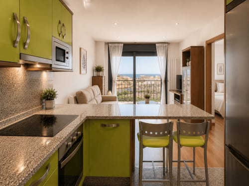 Cocina moderna con muebles verde lima, encimera de granito y barra en apartamento de Baiona con vistas al mar