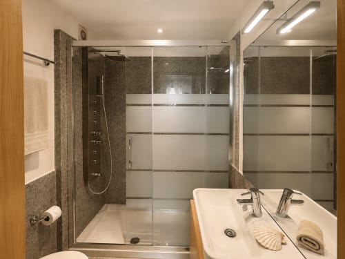 Baño moderno en apartamento Holibai, Baiona con doble lavabo, ducha abierta con puertas de cristal esmerilado y suelos climatizados