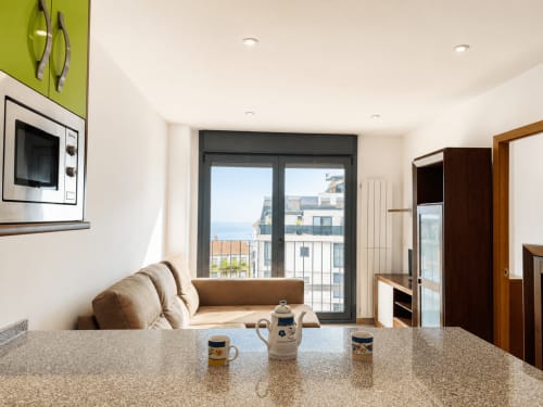Cocina y sala de estar modernas en el apartamento Afouteza, Baiona con balcón con vistas al mar y mobiliario contemporáneo
