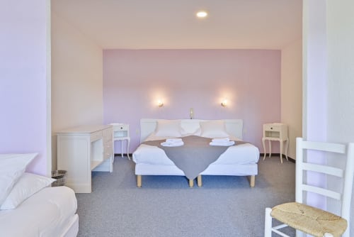Chambre moderne pour 3 personnes à l'Hôtel Le Verdon avec lits jumeaux, mur d'accent rose et vue sur le lac aux Salles sur Verdon