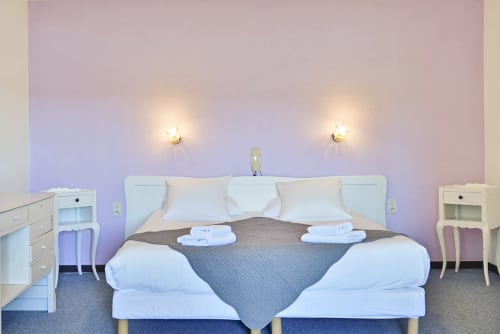 Chambre moderne à l'Hôtel Le Verdon avec vue sur le lac, lit double, draps blancs et éclairage ambiant