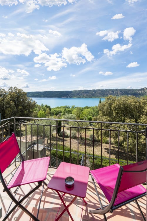 Chaises longues rose sur la terrasse avec vue sur le lac turquoise de l'Hôtel Restaurant Le Verdon aux Salles sur Verdon