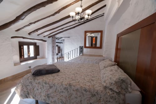 Habitación loft rústica en El Batán Hotel Spa con vigas vistas, paredes blancas y ropa de cama floral en Castillo de Locubín