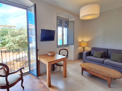 Sala de suite a l'Hotel Casa Calella a Calella de Palafrugell amb sofà, mobles de fusta i balcó amb vistes al mar