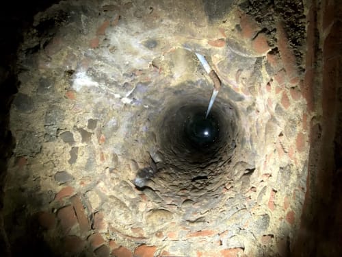 Vue intérieure du conduit de cheminée en pierre d'une chaumière gîte rustique en Ariège avec foyer