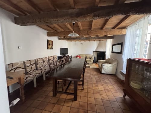 Spacieux séjour du gîte avec poutres apparentes, table à manger, cheminée et coin détente au Gîte du Mercadal à Verniolle