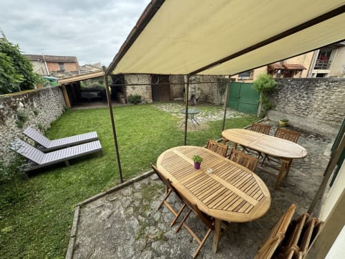 Paisible cour de gîte avec mobilier bois, transats et store rétractable crème sur pierre