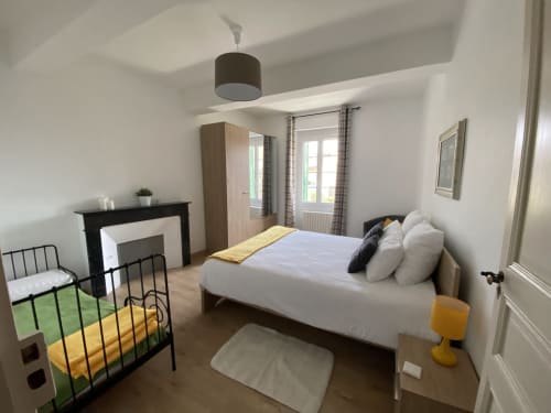Chambre lumineuse au Gîte du Mercadal à Verniolle avec lit queen-size, cheminée, penderie et vue sur le jardin