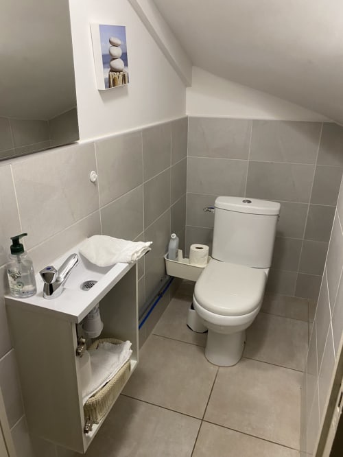 Salle de bain moderne et épurée avec carrelage blanc, toilettes, lavabo et équipements au Gîte du Mercadal à Verniolle