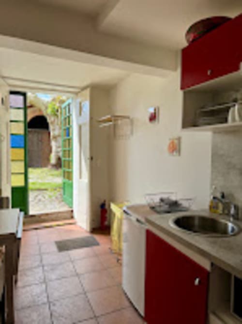 Cuisine moderne aux placards rouges et évier en inox du gîte du Mercadal à Verniolle, Ariège, vue sur le jardin