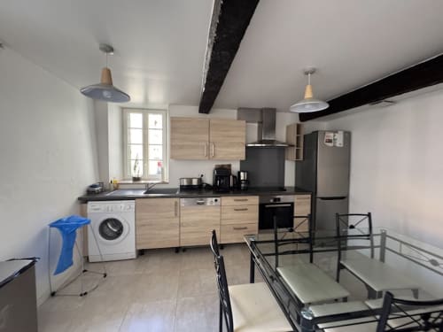 Cuisine moderne du Gîte du Cœur du Village avec meubles en bois, appareils en inox, coin repas et luminaires suspendus