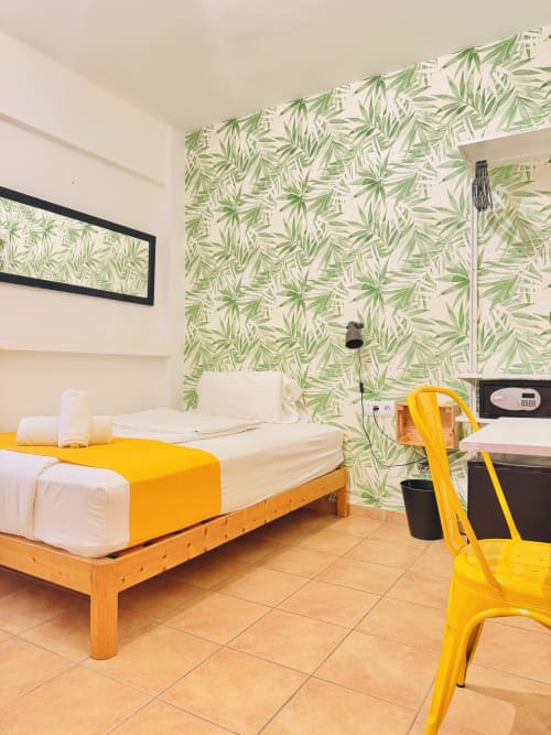 Camera luminosa a Nanit Rooms Ibiza con letto in legno, accenti gialli, carta da parati tropicale e servizi moderni