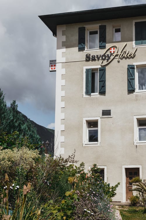Façade du Savoy Hôtel au Bourget-du-Lac, crème avec volets foncés et jardin