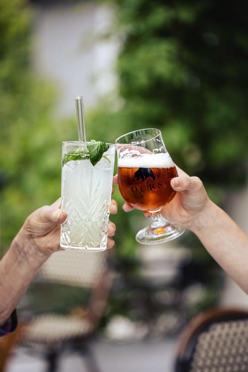Deux personnes trinquent avec un cocktail à la menthe frais et une bière brune au Savoy Hôtel du Bourget-du-Lac
