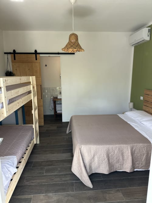 Camera quadrupla Cilento Rooms ad Agnone con letti a castello in legno, letto singolo e lampada a sospensione in vimini