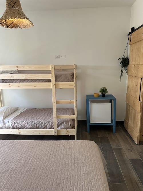 Camera quadrupla Cilento Rooms ad Agnone con letti a castello, letto singolo, comodino blu, armadio in legno e lampadario in vimini