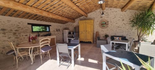 Rustic stone common room at Mas de la Lance B&B with wooden beams, dining table, and seating area in