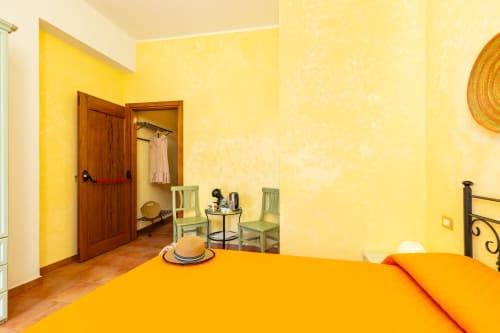 Bright yellow bedroom with orange bedding at Agriturismo Chiai Francesco in Bari Sardo, Italy
