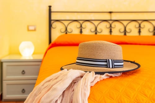 Straw hat on orange bed at Agriturismo Chiai Francesco B&B in Bari Sardo, Italy