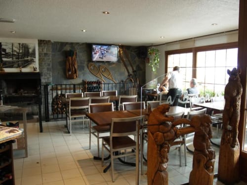 Salón del Hotel Llibrada en Benasque con esculturas de oso talladas en madera, chimenea y decoración de refugio de montaña