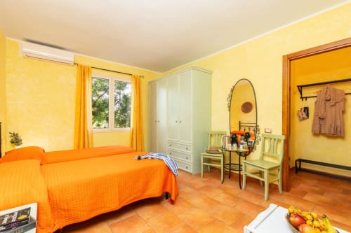 Bright yellow bedroom with orange bed at Agriturismo Chiai Francesco in Bari Sardo, Italy