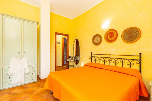 Bright yellow bedroom with orange bed at Agriturismo Chiai Francesco in Bari Sardo, Italy