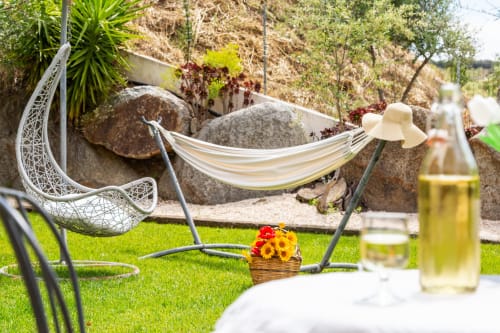 Relaxing garden setup at Agriturismo Chiai Francesco with hammock, hanging egg chair, and fresh flowers in Bari Sardo