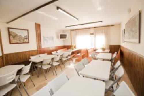 Aula moderna o sala de reuniones del Hotel Llibrada en Benasque con mesas blancas, sillas y paneles de madera