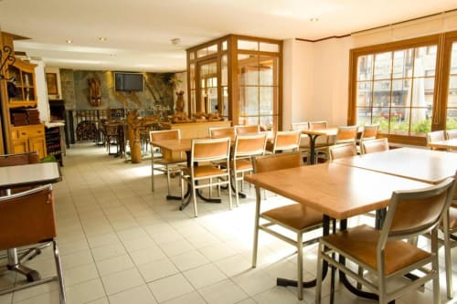 Comedor del Hotel Llibrada en Benasque con mesas de madera, sillas beige y grandes ventanales