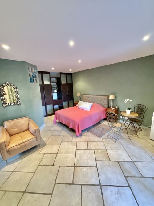Chambre spacieuse au Domaine Pero Longo avec literie corail, murs vert sauge, carrelage et coin salon
