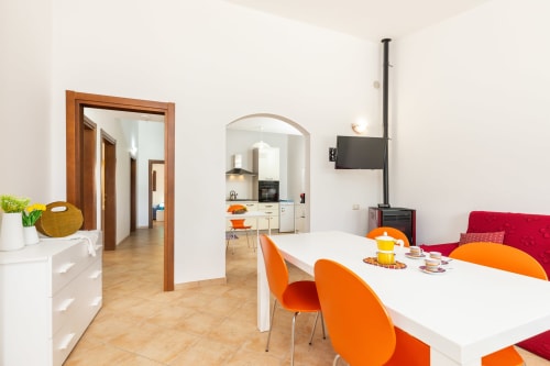 Modern open-plan living area at Agriturismo Chiai Francesco in Bari Sardo with orange chairs, white table, and kitchen access
