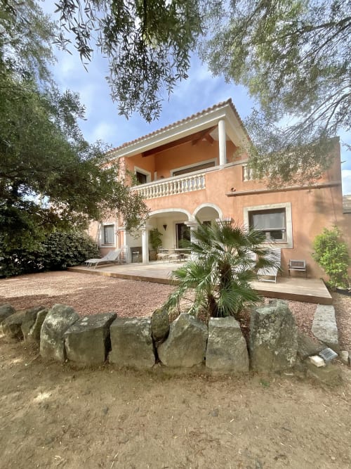 Appartement Domaine Pero Longo à Sartène avec terrasse, murs en pierre, palmier et façade rose pêche