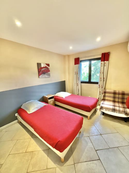 Chambre twin aux draps rouges à l'appartement Domaine Pero Longo à Sartène, Corse, avec accès au balcon
