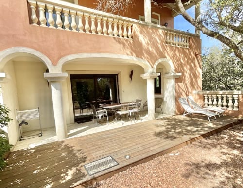 Terrasse de l'Appartement Bavella à Sartène avec coin repas, transats et portes cintrées donnant sur le jardin