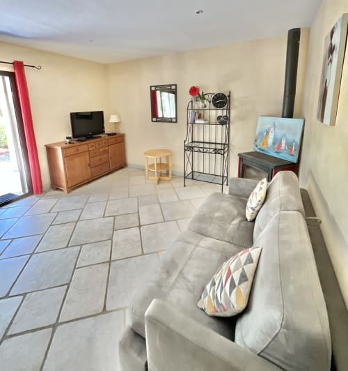 Salon ensoleillé de l'Appartement Bavella au Domaine Pero Longo, Sartène avec canapé gris, TV, commode en bois et carrelage
