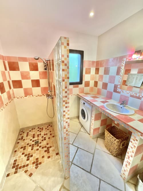 Salle de bain moderne aux carreaux rouges et blancs, douche à l'italienne, lavabo et lave-linge au Domaine Pero Longo