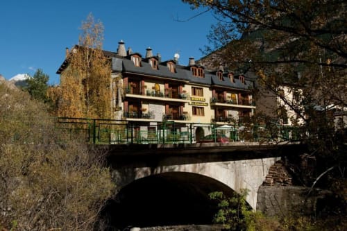 Hotel Llibrada en Benasque, España, con puente de piedra y vistas a las montañas