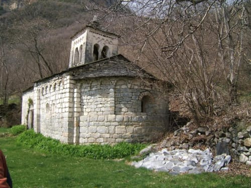 Capilla de piedra histórica rodeada de árboles desnudos y césped verde en el Hotel Llibrada de Benasque, España