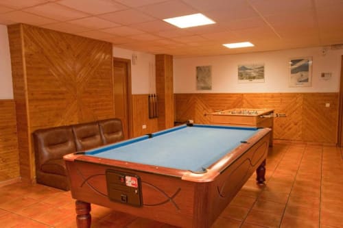 Sala de juegos del Hotel Llibrada en Benasque con billar, futbolín y revestimiento de madera