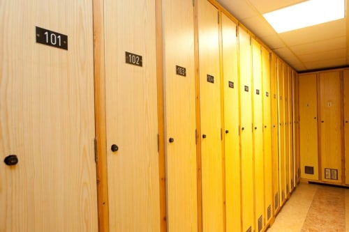 Pasillo con taquillas numeradas en el Hotel Llibrada de Benasque, con puertas de madera e iluminación.