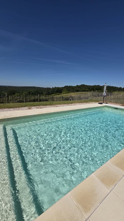 Piscine cristalline avec terrasse au Home Sweet Lodge Glamping en Aquitaine, entourée de la campagne et d'une clôture en bois